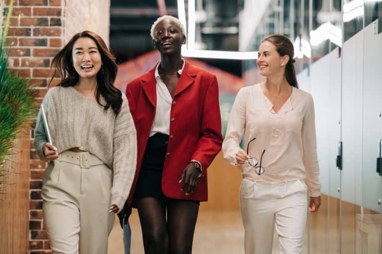 Trois femmes épanouies avancent d'un pas décidé au sein de leur environnement de travail. Leurs sourires témoignent de leur réussite dans la quête de l'épanouissement professionnel.