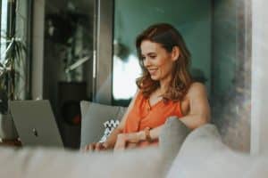 Une femme souriante assise devant son ordinateur, symbole de l'entrepreneuriat tout en restant salariée.